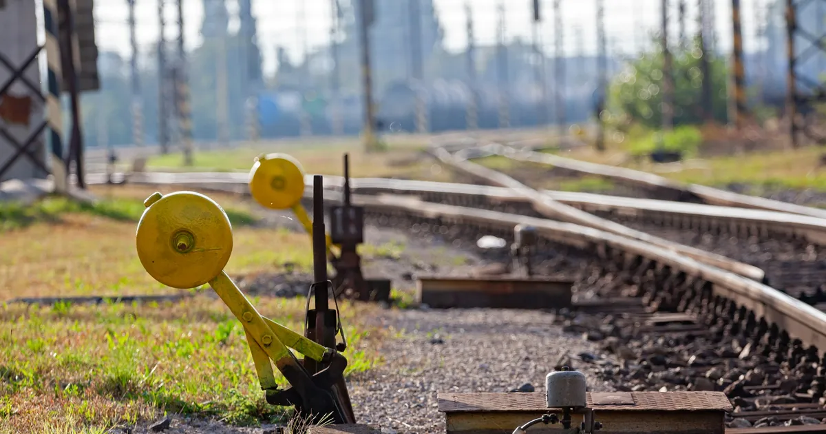 Yellow-weighted railway track switches beside diverging rails in daylight