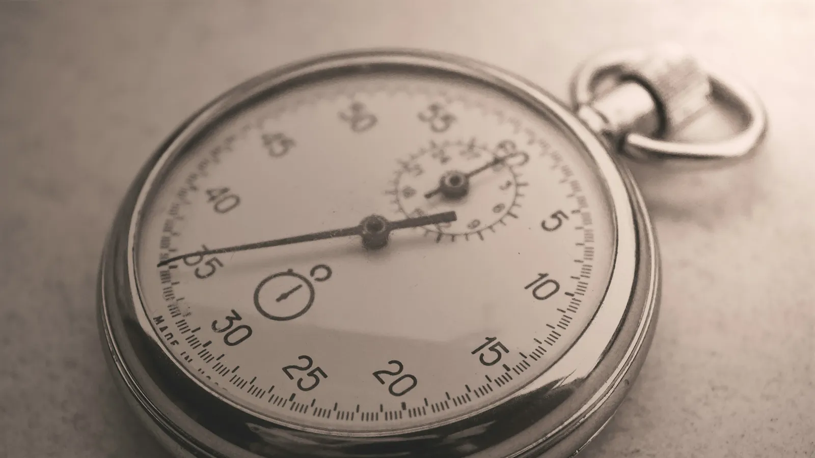 A silver pocket watch lying on a wooden surface