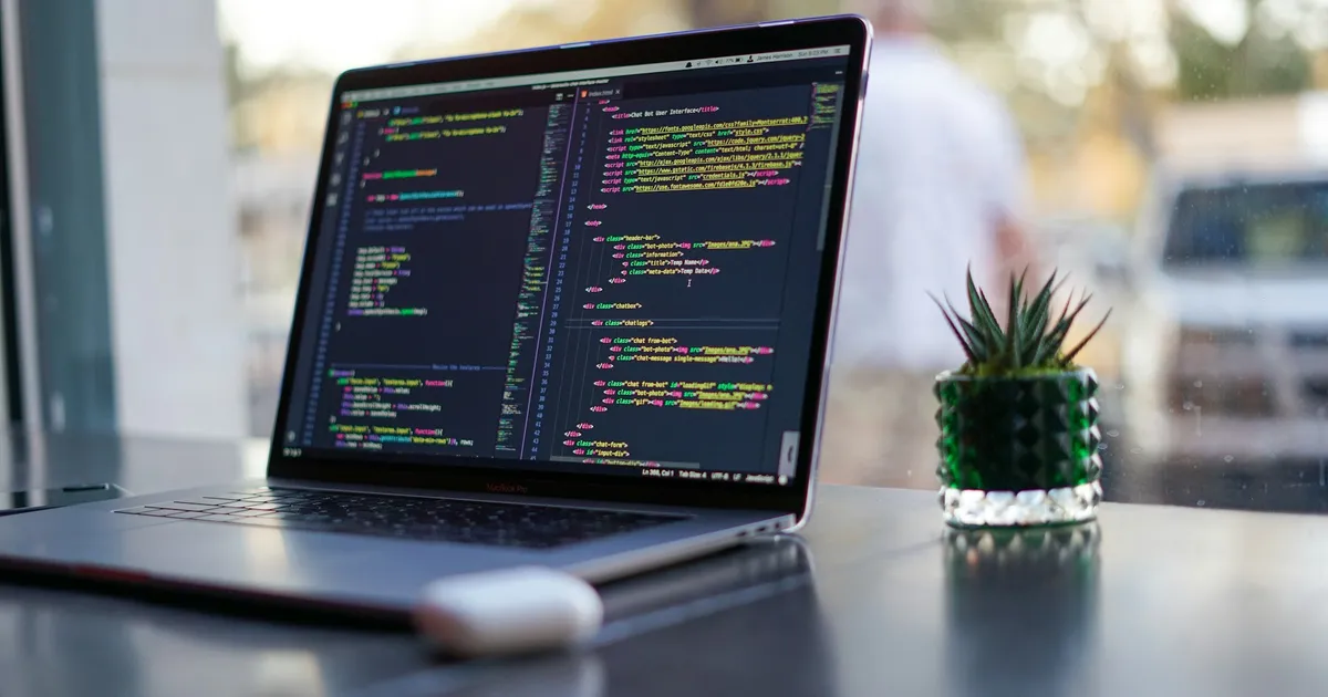Laptop showing source code on a table in a coffee shop