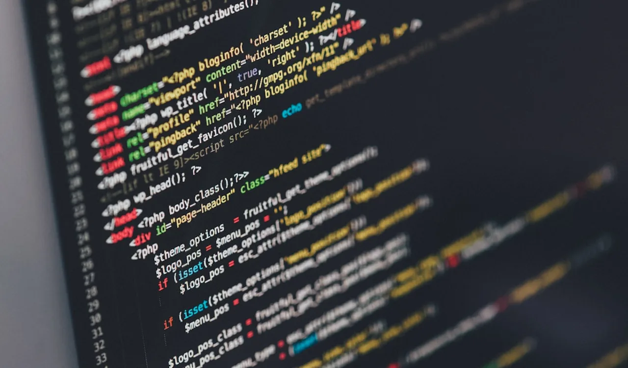 A developer writing TypeScript code on a monitor with an AI assistant panel open alongside the editor
