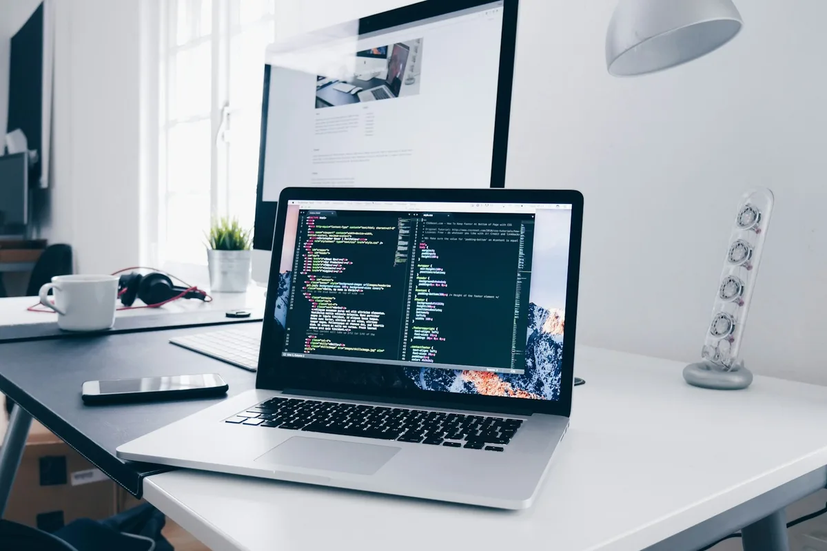 MacBook with lines of code on a busy desk
