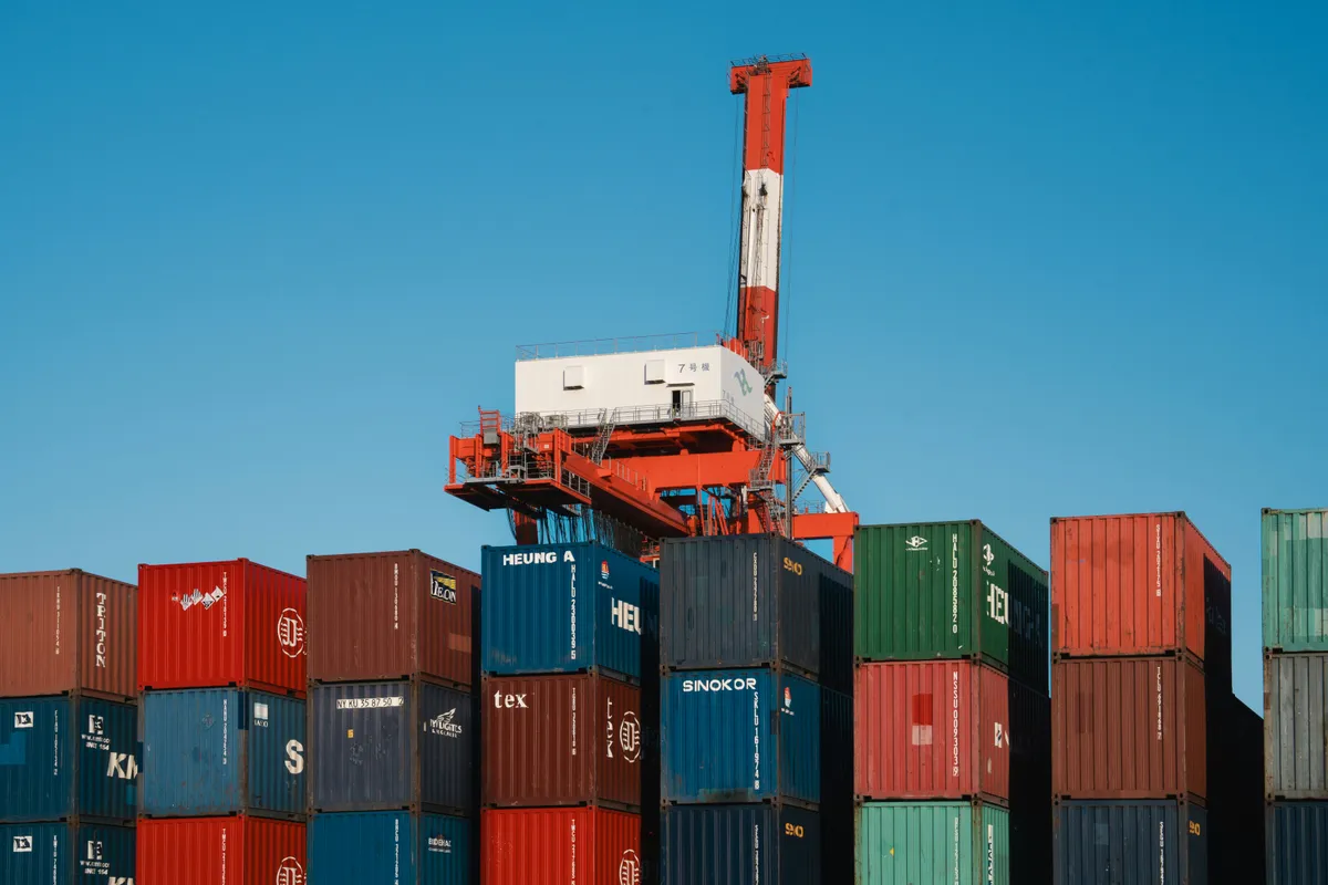 Gantry crane lifting above a block of colourful port containers