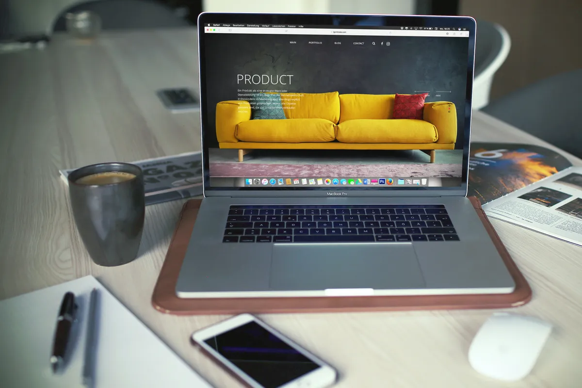 A laptop on a desk displaying a product website layout beside a phone