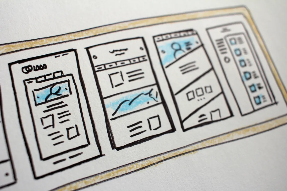 Hand-drawn wireframe sketches of app screen layouts on paper