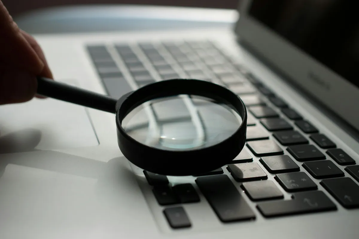 A magnifying glass resting next to a laptop keyboard, symbolizing code inspection