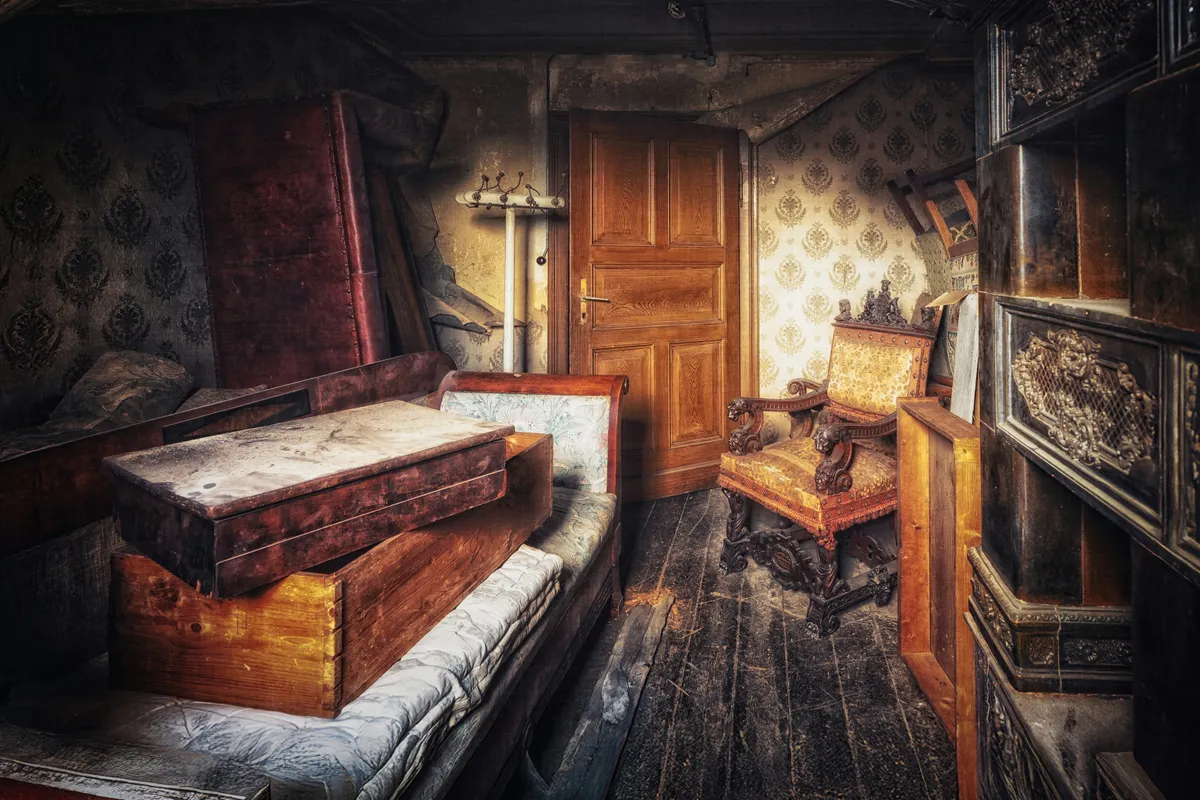 Disused room with dusty furniture and peeling wallpaper