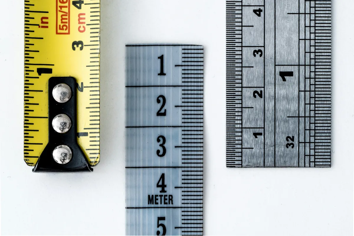 Three overlapping rulers and tape measures showing different measurement scales