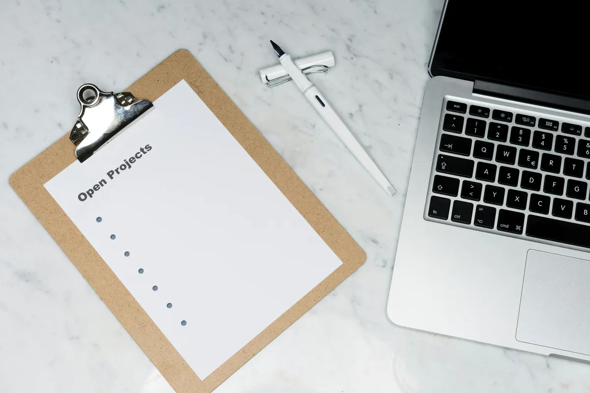 Printed task checklist on a clipboard resting next to a laptop