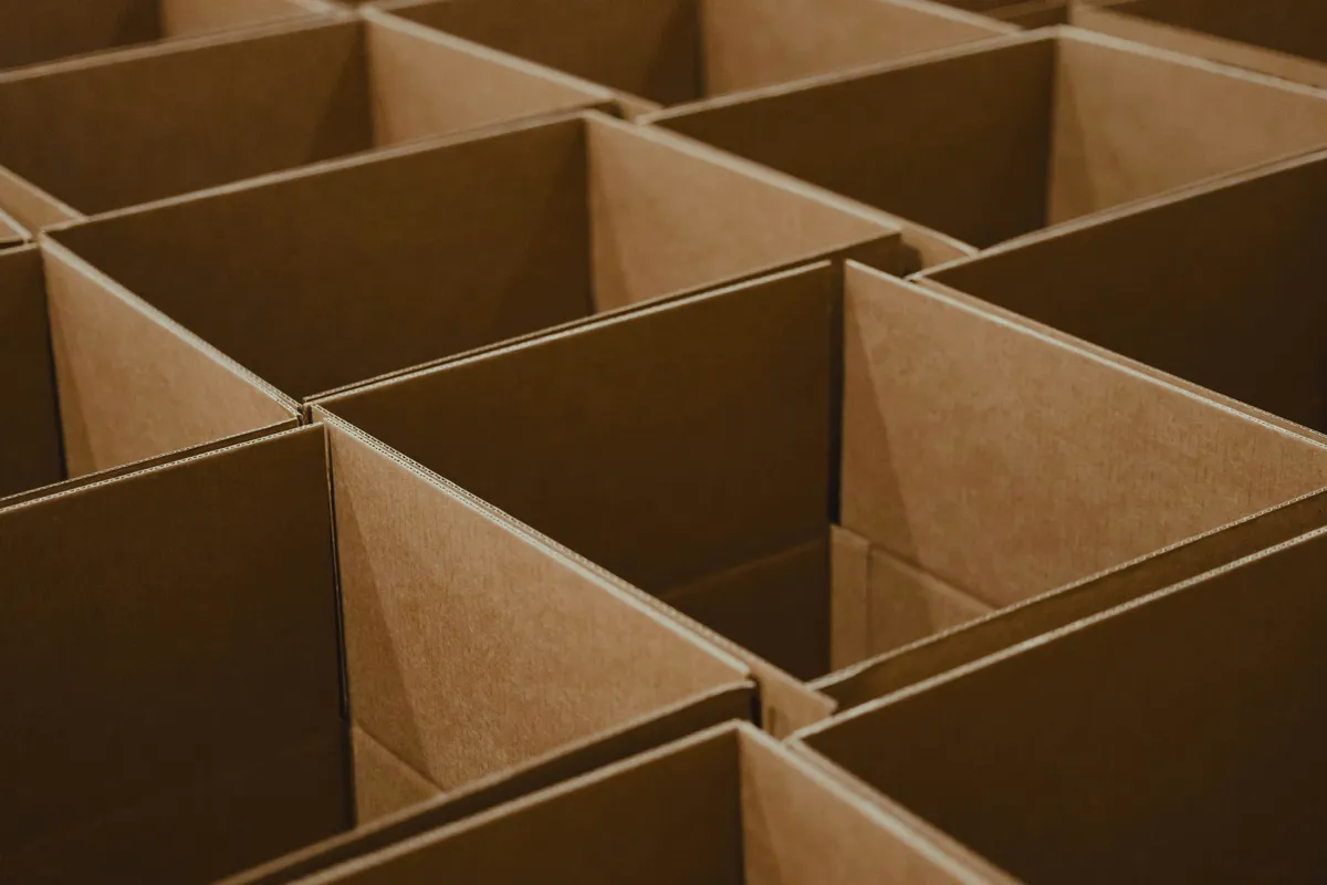 Open cardboard boxes stacked on the floor of an empty room
