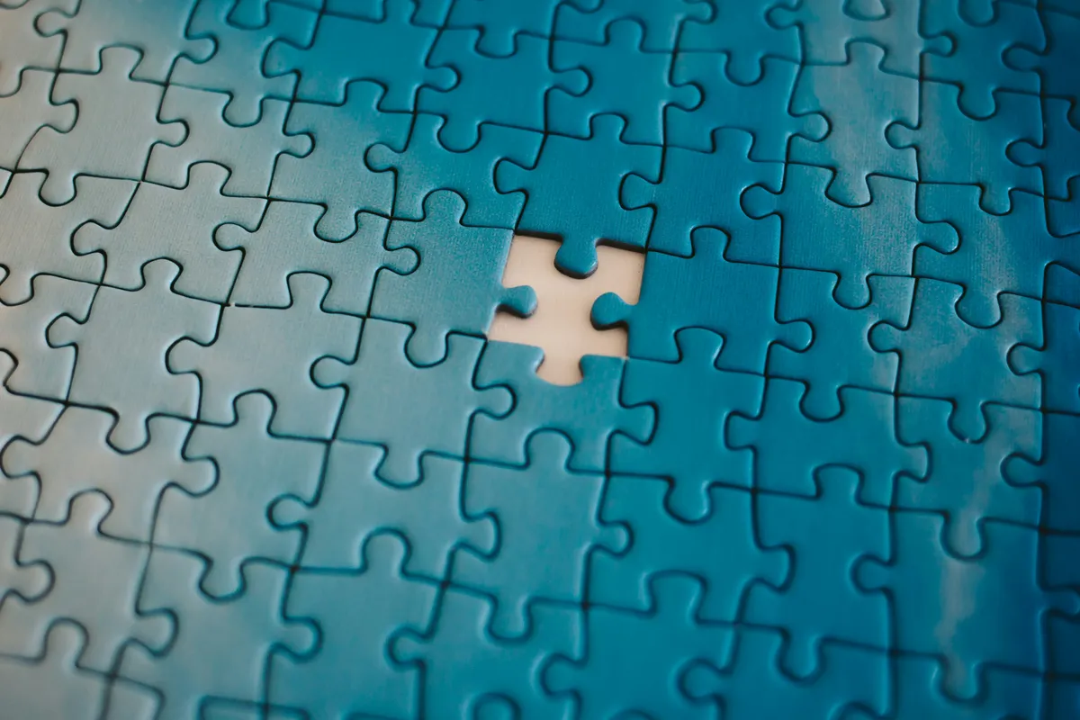 A blue jigsaw puzzle with a single piece missing from the middle