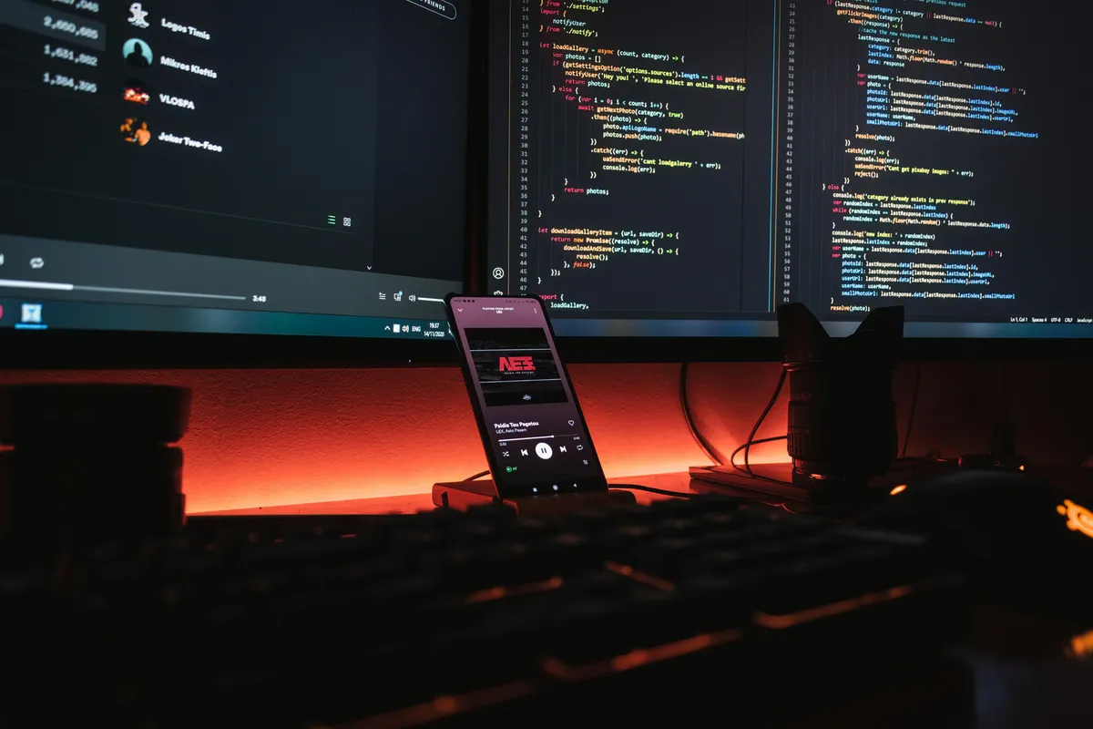 A desk with two monitors showing code, lit by warm ambient light at night