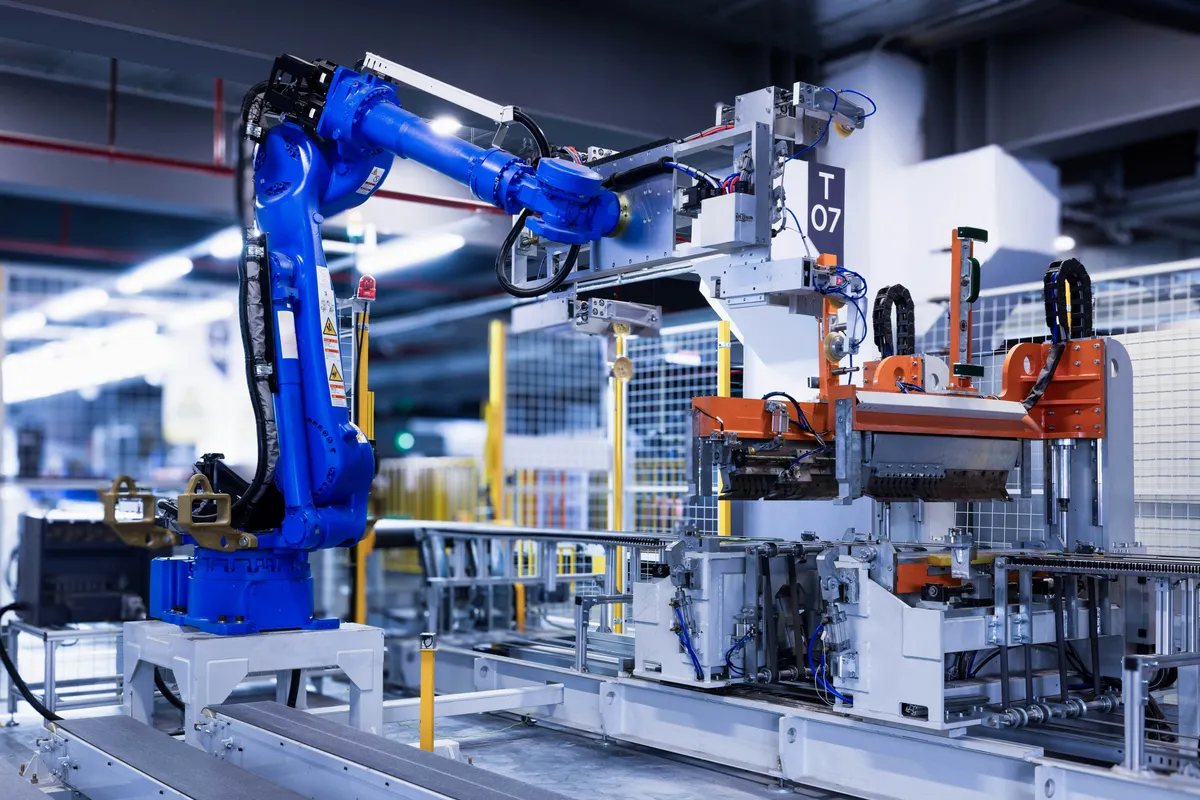 Blue industrial robot arm working alongside other machines on a factory line