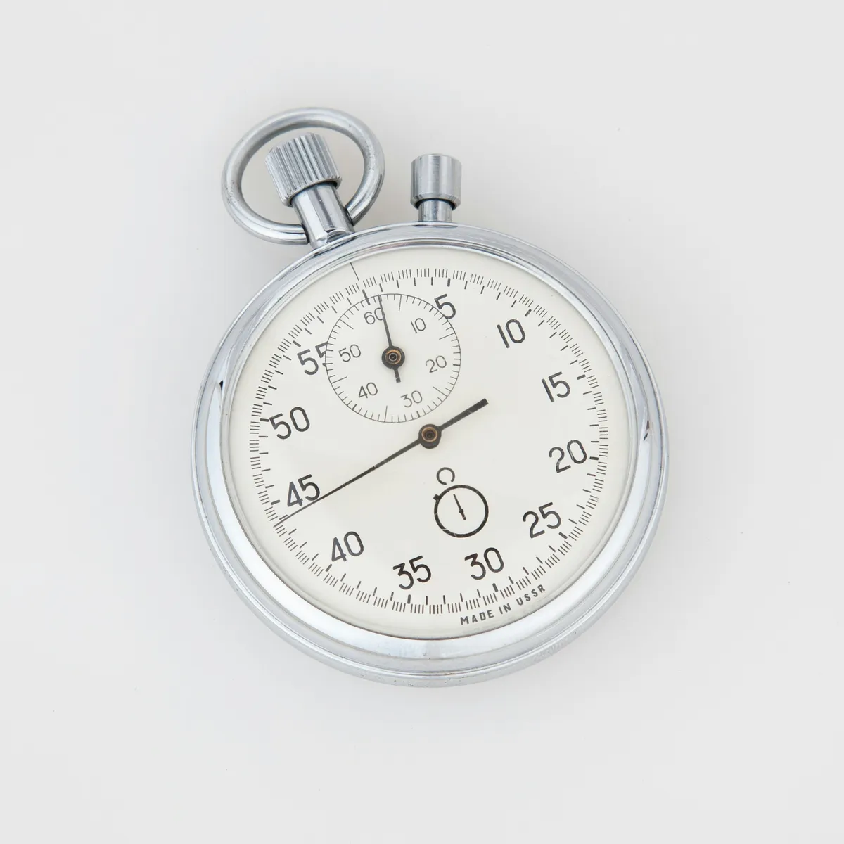 Silver analog stopwatch lying face-up, symbolizing precise timing measurement