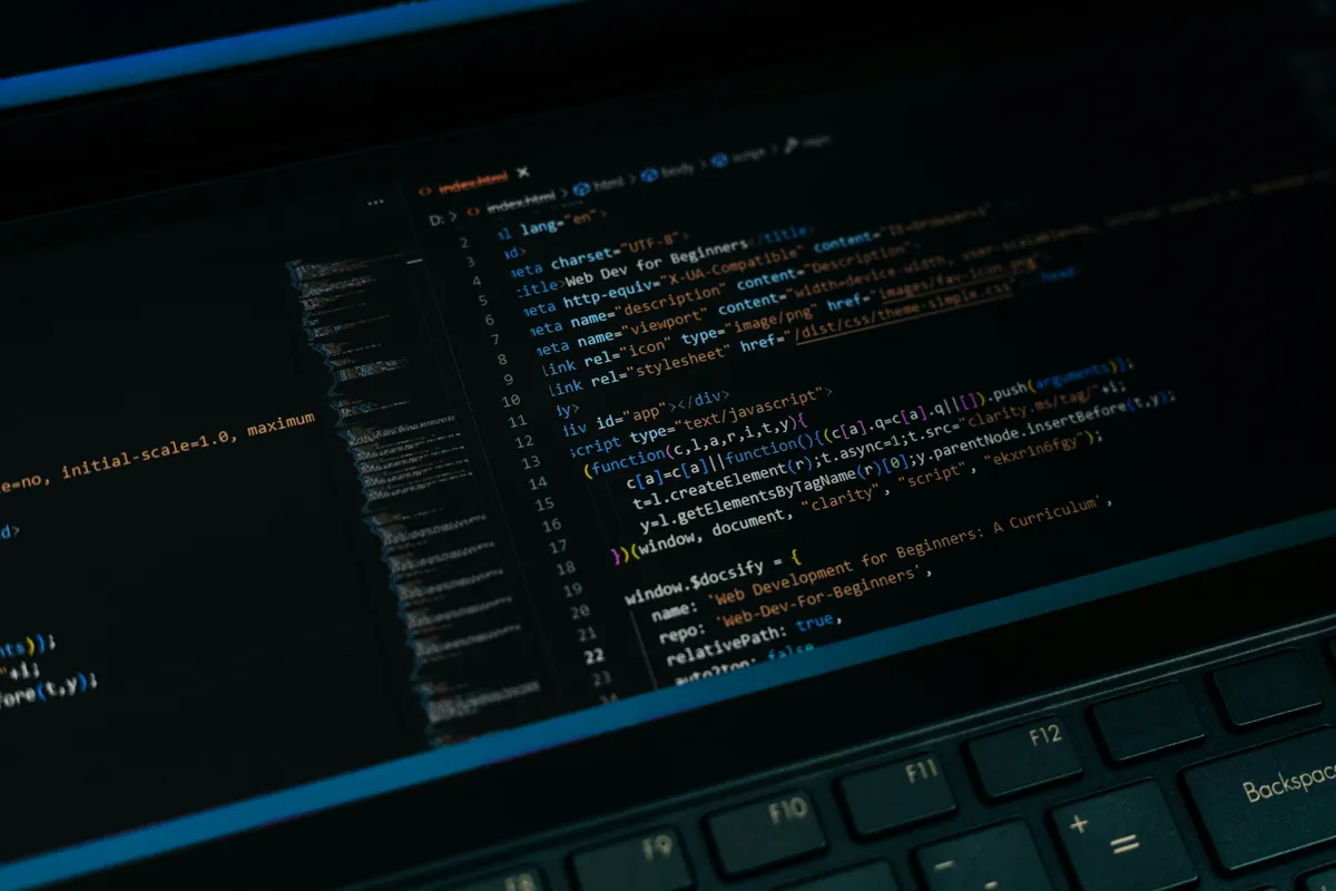 Lines of JavaScript code glowing on a laptop screen in a dark editor