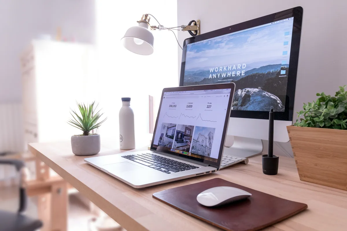 A tidy developer workspace with an iMac and a MacBook on a wooden desk