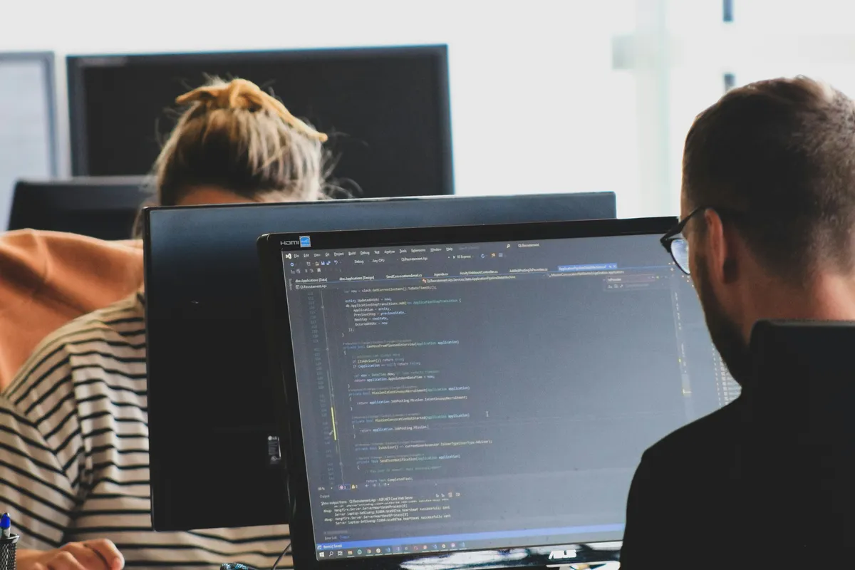 Two developers reviewing code together on a shared monitor