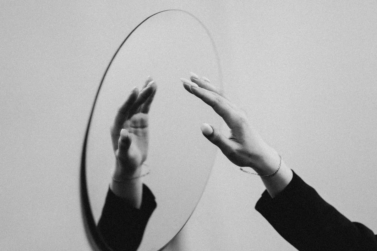 A hand reaching toward its own mirror image, symbolizing an identical copy