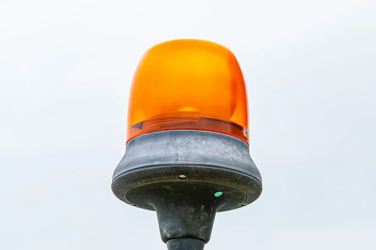 An amber warning beacon light mounted on a post, signaling an active alert