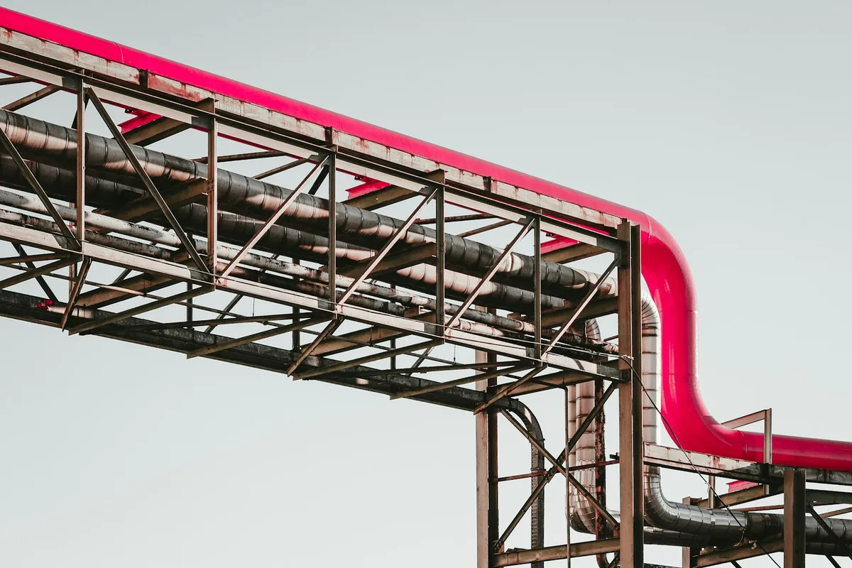 A bright pink industrial pipe running along a metal support structure