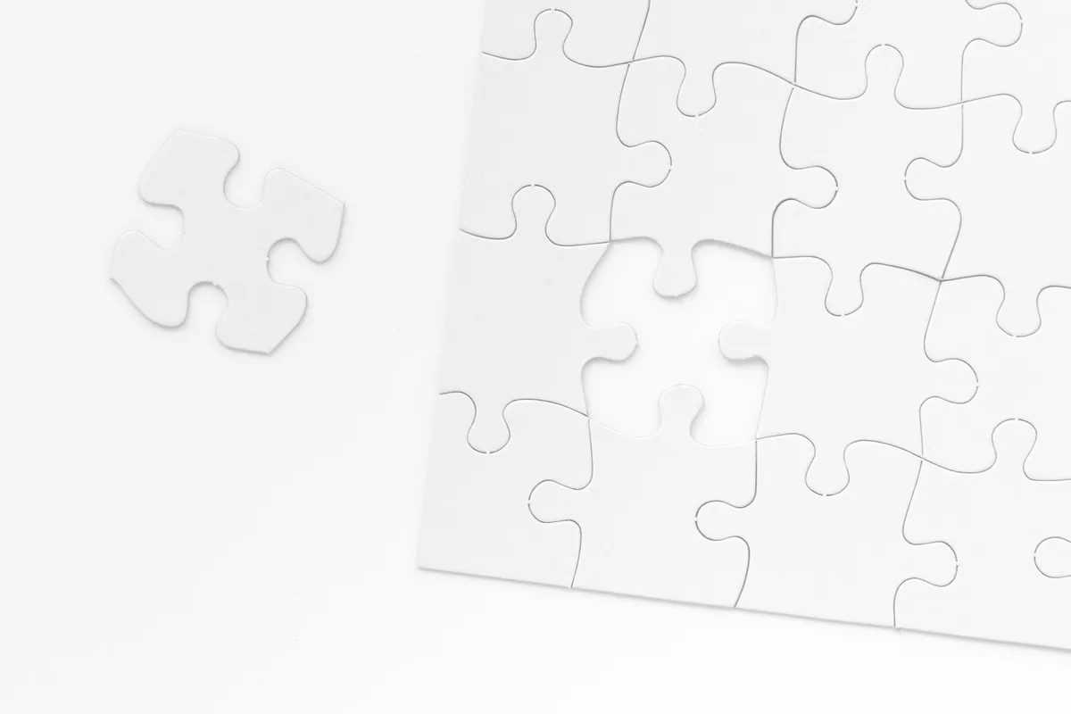 A white jigsaw puzzle with one missing piece beside it